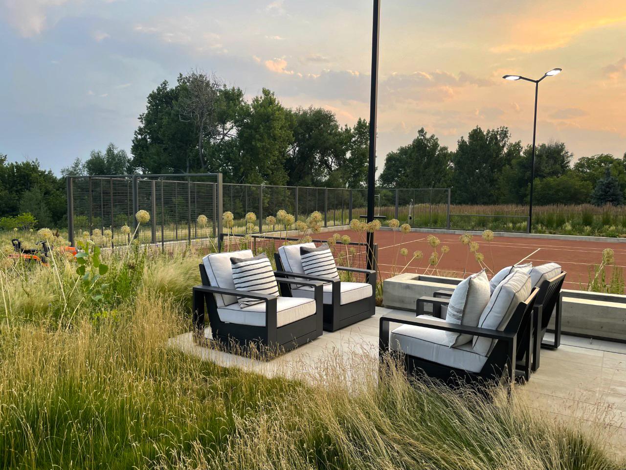 Contemporary luxury home with expansive glass walls, flat roofs, and a long reflecting pool overlooking a landscaped lawn.