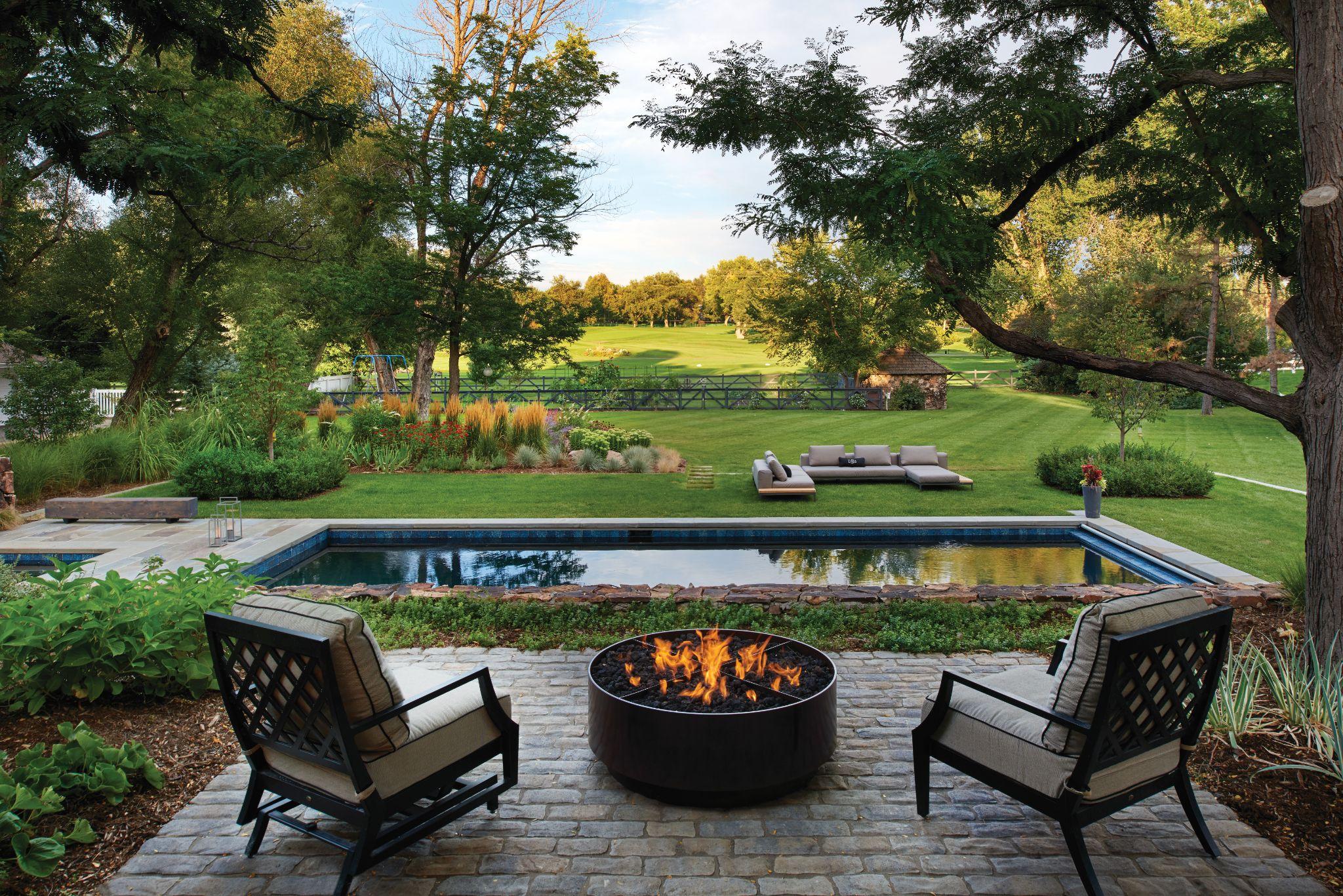 Poolside fire pit patio with expansive landscaped lawn