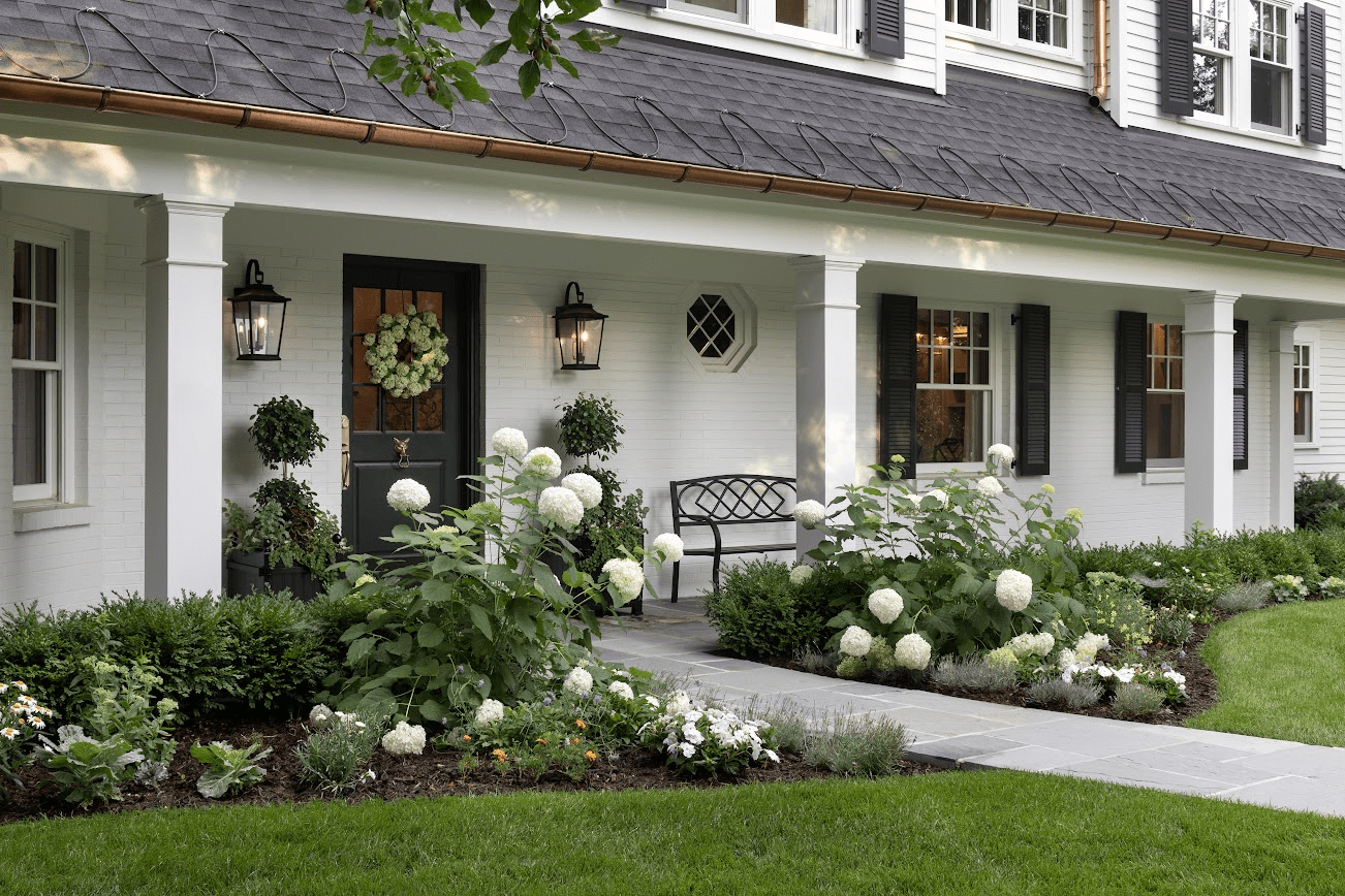 A colonial home with a hardscape pathway framed by white hydrangeas.